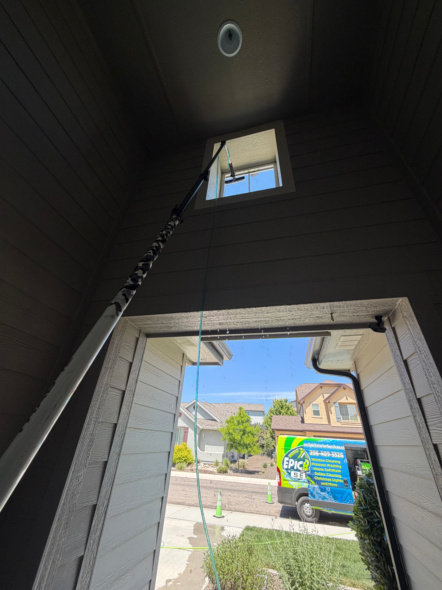 Exterior entryway transom window cleaning with Epic Exterior Services van visible outside