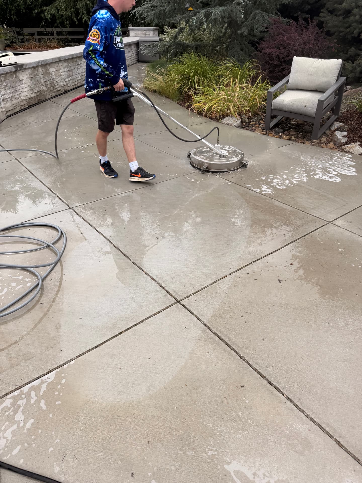 Epic Exterior Services technician surface cleaning a concrete pool patio in Eagle, Idaho